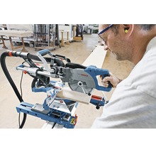 Eine Person bedient eine Bosch Kapp- und Gehrungssäge beim Sägen eines Werkstücks.