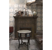 Dekoratives Interieur mit dunklem Holzofen, Beistelltisch mit floralen Motiven und antikem Spielzeugdreirad.