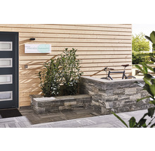 Außenbereich eines Gebäudes mit Pflastersteinen, Holzwand und Tür