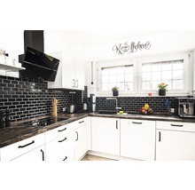 Moderne Küche mit weißen Schränken, dunkler Arbeitsplatte und schwarzen Fliesen