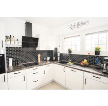 Helle Küche mit schwarzen Fliesen und moderner Ausstattung.