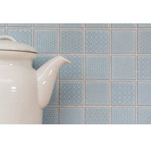 Dekorative quadratische Wandfliesen mit Mustern hinter einer Teekanne