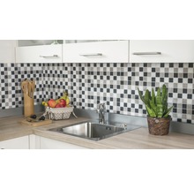 Küchenspüle mit Armatur, Mosaikfliesen und Küchenutensilien auf einer Küchentheke