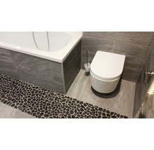 Badezimmer mit Badewanne, Toilette und Steinboden