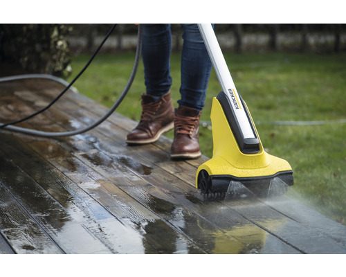 Person reinigt eine Holzterrasse mit einem Kärcher Terrassenreiniger