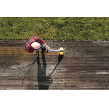 Person reinigt Holzterrasse mit Hochdruckreiniger