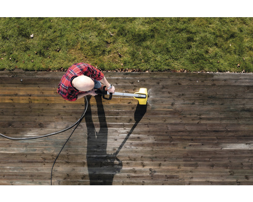 Person reinigt Holzterrasse mit Hochdruckreiniger