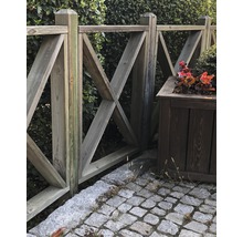 Holzzaun mit dekorativem X-förmigem Muster und Pflanzkasten im Garten