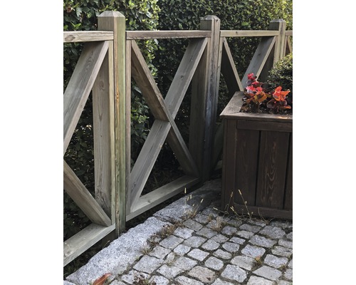 Holzzaun mit dekorativem X-förmigem Muster und Pflanzkasten im Garten