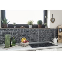 Küchenszene mit Mosaikfliesen, Fensterbank mit Pflanzen, Obstkorb und Kochfeld.