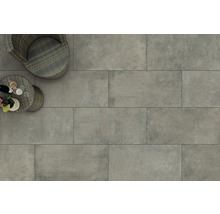 Bodenansicht mit grauen Terrassenfliesen, Rattansessel und kleinem Tisch