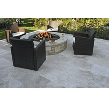 Gartenszene mit Feuerstelle, Steinfliesen und Korbsesseln