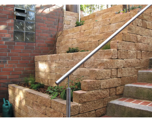 Gestufte Gartenmauer aus Natursteinen mit Edelstahlgeländer und Bepflanzung