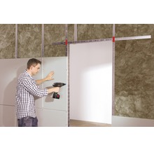 Mann befestigt eine Gipskartonplatte mit einem Akku-Bohrschrauber an einer Metallunterkonstruktion