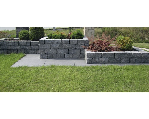 Gartenlandschaft mit Rasen, Wegplatten und bepflanzten Mauerblöcken