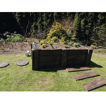 Hochbeet aus Holz im Garten mit Bepflanzung, Gießkanne und Gartenwerkzeug