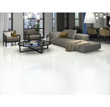 Heller Wohnraum mit glänzenden Bodenfliesen, Sofa, Sesseln und Tisch