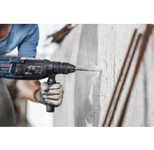 Ein Arbeiter bohrt mit einer Bohrmaschine in eine Betonwand.