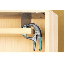 Eine Einhandzwinge fixiert ein Werkstück an einem Möbelstück.