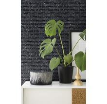 Dekorative Wandgestaltung mit Mosaikfliesen in einem Raum mit Zimmerpflanzen und Dekorationselementen.