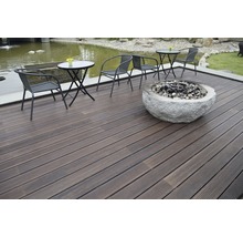 Terrasse mit dunklen Holzdielen, Sitzgruppe und Feuerstelle aus Stein.