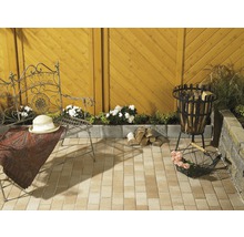 Gestalteter Gartenbereich mit Sitzgelegenheit, Feuerstelle und Holzstapel auf Pflastersteinen