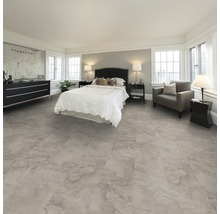 Schlafzimmer mit Bett, Kommode, Sessel und Bodenbelag in Steinoptik