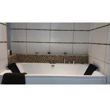 Badezimmer mit Badewanne, Fliesenwand und dekorativen Elementen