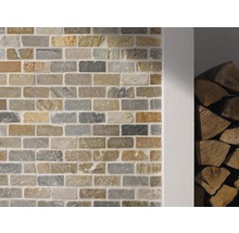 Wand mit Verblendern in Steinoptik und Holzstapel