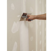 Eine Person glättet Spachtelmasse mit einer Glättkelle auf einer Gipskartonwand.