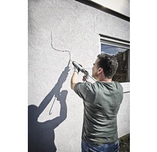 Mann dichtet einen Riss in einer Wand mit einer Dichtpistole ab.