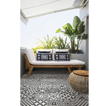 Terrasse mit Holzbett, gemusterten Kissen, Rattantisch und gemusterten Fliesen