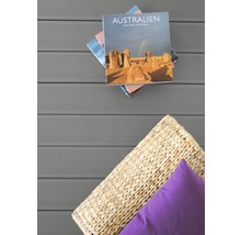 Szene mit Buch, Kissen und Flechtkorb auf Terrassendielen