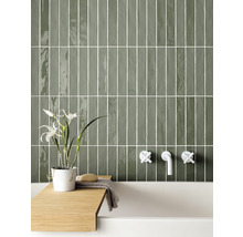 Badezimmer mit grünen Wandfliesen, Armaturen und Badewannenablage