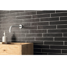 Badezimmerwand mit schwarzen, länglichen Fliesen und einem Holzwandwaschtisch