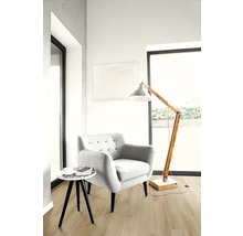 Heller Wohnraum mit Sessel, Stehlampe und kleinem Tisch auf Holzboden