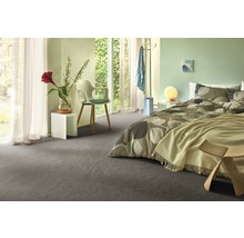 Modernes Schlafzimmer mit grauem Teppichboden, Bett mit Musterbettwäsche und weißen Nachttischen.