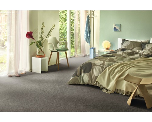 Modernes Schlafzimmer mit grauem Teppichboden, Bett mit Musterbettwäsche und weißen Nachttischen.