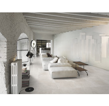 Heller Wohnraum mit Sofa, Bodenfliesen, Heizkörper und Dekorationen.