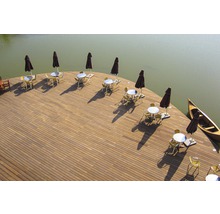 Terrasse am Wasser mit Tischen, Stühlen, Sonnenschirmen und Kanu