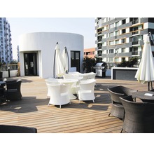 Terrasse mit Gartenmöbeln aus Rattan und Sonnenschirmen vor einem Gebäude