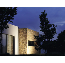 Außenansicht eines modernen Hauses mit Steinverkleidung und Fenster bei Nacht