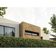 Außenansicht eines modernen Hauses mit Natursteinfassade und begrüntem Hang