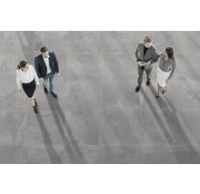 Großformatige, graue Bodenfliesen mit vier Personen von oben fotografiert.