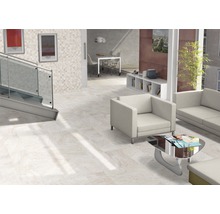 Heller Raum mit Bodenfliesen, Treppe, Sitzbereich und Dekorationen für ein modernes Wohnambiente.