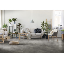 Heller Wohnraum mit Sofa, Stühlen, Pflanzen und Bodenfliesen in Steinoptik