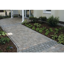 Gepflasterter Weg zu einem Haus mit bepflanzten Beeten