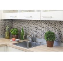 Küchenspüle mit Armatur, Mosaikfliesen, Küchenschränken und Dekorationen wie einer Ananas und einem Topf Basilikum