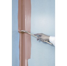 Eine Person streicht mit einem Pinsel eine Leiste an einer Wand.