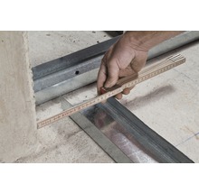 Hand misst Abstand zwischen Metallprofilen mit einem Gliedermaßstab